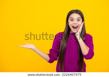 Wow, it's unbelievable. Shocked teenager child pointing aside at copy space. Teen girl pointing with two hands and fingers to the side. Excited face. Amazed expression, cheerful and glad.