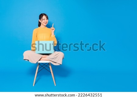 Young Asian woman using a laptop PC on blue background. Internet guidance.
