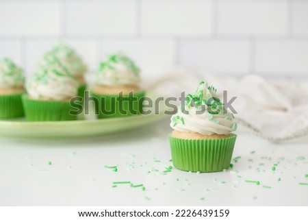 Vanilla Cupcakes with Buttercream Frosting and Green Sprinkles on White Kitchen Counter Royalty-Free Stock Photo #2226439159