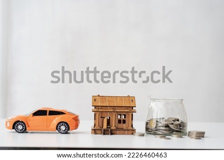 Piggy bank and toy car house on the table backdrop. white color concept of saving money for a house car