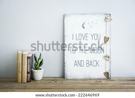 motivational inspirational poster quote LOVE YOU TO THE MOON AND BACK. Room decoration american or scandinavian style  with books, succulent in the pot and heart shaped garland.