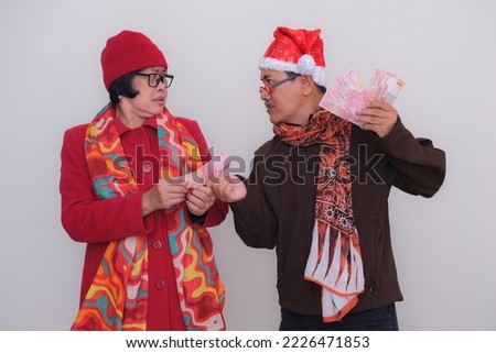 Husband and wife in Christmas costume, distributing money for shopping. Merry Christmas 2022
