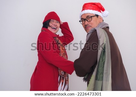 Husband and wife getting ready to go out wearing warm clothes in winter. Happy Christmas 2022.