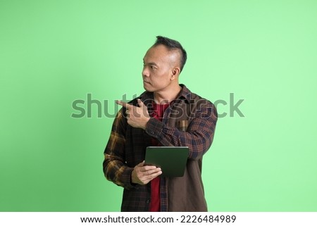 The 40s adult Asian man with plaid shirt standing on the green background.