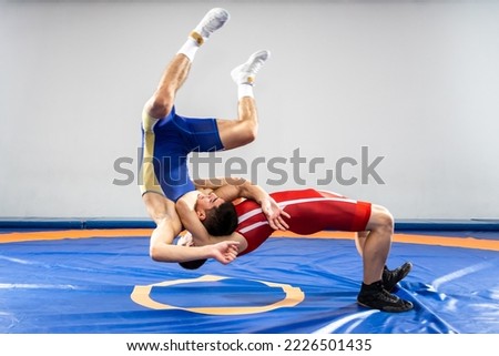 The concept of fair wrestling. Two greco-roman  wrestlers in red and blue uniform wrestling   on a wrestling carpet in the gym.The concept of fair wrestling