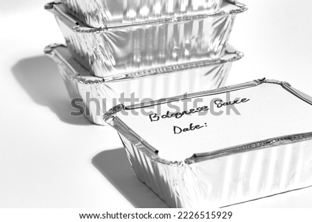 Individual foil tray containers filled with homemade bolognese sauce ready for freezing. Ideas for cutting the cost of food. Royalty-Free Stock Photo #2226515929