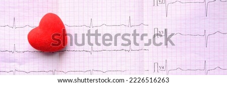 Panoramic view on red heart on sheet of pink millimeter paper with diagram of medical examination of the heart on an electrocardiogram with copy space. Medical concept and widescreen wallpaper Royalty-Free Stock Photo #2226516263