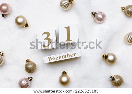 Happy New Year holiday concept, calendar with date 31 december. Christmas shiny balls on white fake fur background. Golden, pale pink color Xmas metallic balls, Happy holidays card, top view, flat lay