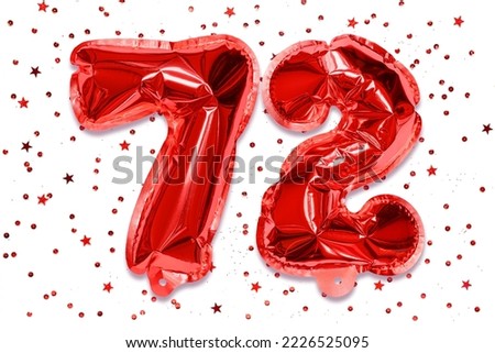 The number of the balloon made of red foil, the number seventy two on a white background with sequins. Birthday greeting card with inscription 72. Numerical digit. Celebration event. Royalty-Free Stock Photo #2226525095
