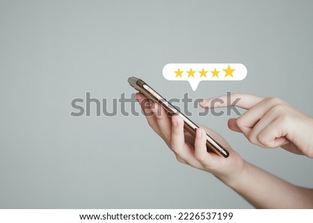Customer hand press on smartphone screen and give five star excellent rating for giving best score point to review the service, Customer experience, Evaluation, Satisfaction, Feedback, Review concept.