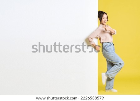 image of Asian girl standing and posing with billboard Royalty-Free Stock Photo #2226538579