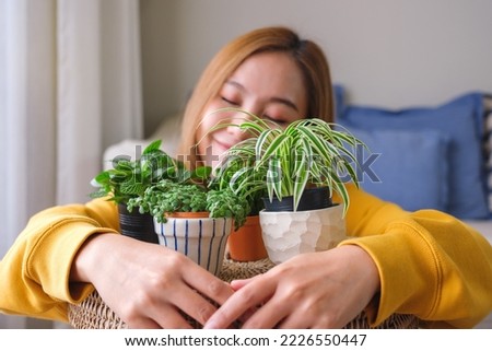 Portrait image of a beautiful young woman holding and hugging houseplants at home Royalty-Free Stock Photo #2226550447