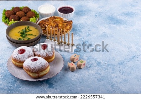 Traditional Jewish holiday Hanukkah food. Doughnuts sufganiot, potatoes pancakes latkes, falafel, candle and dreidl