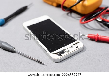 Close up of Smartphone with broken screen on electronic store workbench. Repairing damaged mobile phone concept
