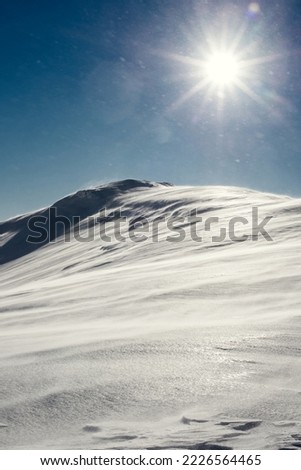 Bright sun over the snow-capped mountain peak. Winter landscape. Photo was made during a snowstorm.