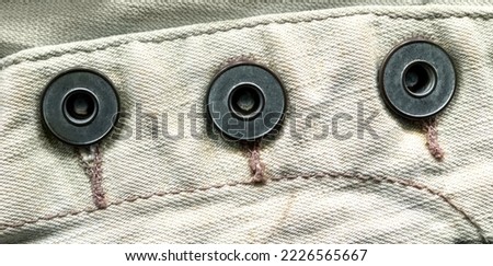 Iron buttons on white denim. Stock photo of high quality fabric.