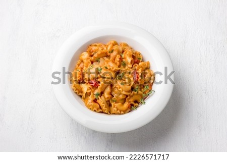 Simple pasta with tomato sauce sprinkled with fresh thyme in a white plate on a light gray background, top view, flat lay. Delicious homemade food