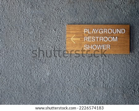 A Playground, restroom and shower sign wooden board hanging on shabby concrete cement wall. Place for logo, sign or text