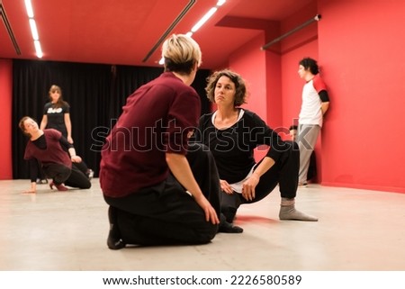 Two young women on their knees look at each other's faces with a sad expression, in a show of body theater Royalty-Free Stock Photo #2226580589