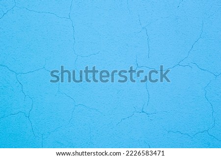 Photo of a blue concrete wall with a lot of cracks in the plaster