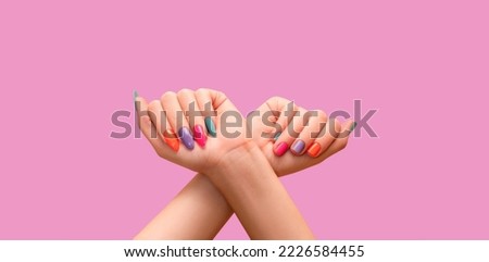 Female hands: one with long colorful nail design and other with short nail design. Glitter nail polish manicure: purple, green, pink, and orange. Female model hands with perfect colorful manicure on p Royalty-Free Stock Photo #2226584455