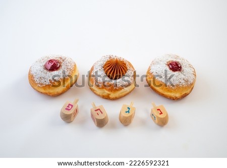 Fresh donuts with jelly and chocolate with  wooden dreidels  for Hanukkah celebration. Hebrew letters on wood dreidels say : Great Miracle Happened Hear.