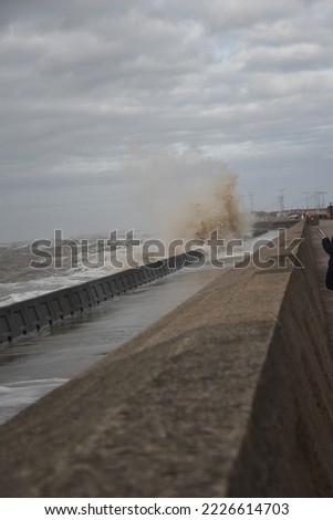 Huge waves crashing over the sea wall with a dark cloudy sky background. Taken in Blackpool England. 