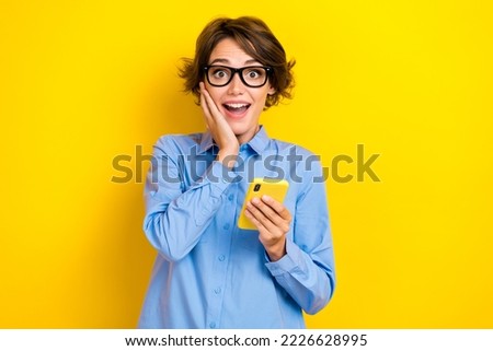 Closeup photo of young attractive funny excited positive surprised woman touch cheeks hold phone eshopping summer sale isolated on yellow color background