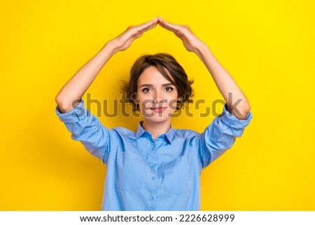 Portrait photo of young attractive nice cute woman bob brown hair girlish demonstrating her new house safety hands symbol isolated on yellow color background