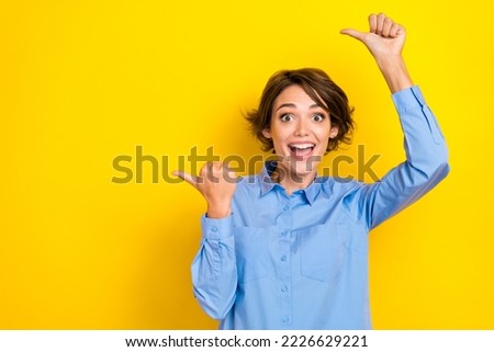 Portrait photo of young funny excited girlish woman wear blue shirt crazy fingers pointing empty space good vacancy isolated on yellow color background Royalty-Free Stock Photo #2226629221