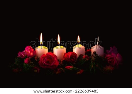 third burning advent candle on decorated rose flower pink advent wreath