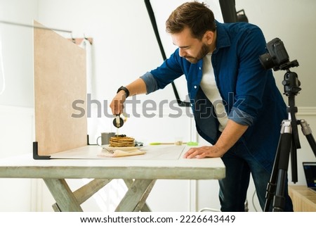 Attractive photographer doing food styling to take professional photo shooting of pancakes at his studio