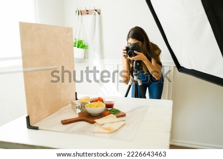 Female photographer using her camera on a tripod while doing food photo shoot 