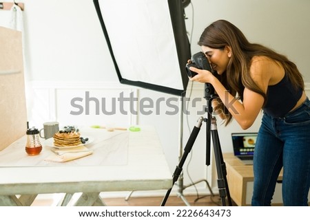 Happy female photographer smiling while doing a photo shooting of food at her professional studio