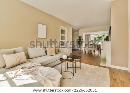 Large corner sofa with soft cushions located under elegant chandelier near fireplace in light living room near kitchen