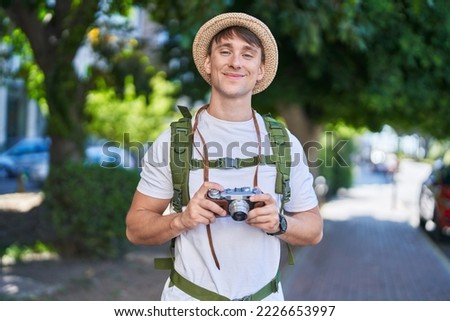 Young caucasian man tourist smiling confident holding vintage camera at park