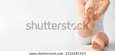 Young woman making foot massage on light background with space for text Royalty-Free Stock Photo #2226681963