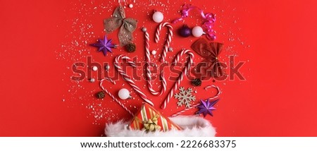 Festive composition with sweet candy canes and Christmas decorations on red background