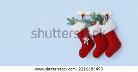 Beautiful Christmas socks hanging on light blue wall Royalty-Free Stock Photo #2226683493