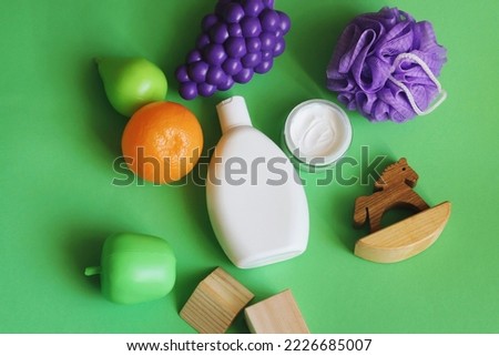 Organic  care shampoo, moisturizing facial cream, sponge and toys on a green background. Natural skin and hair care cosmetic products