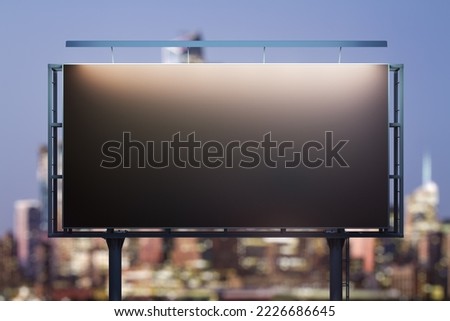 Blank black horizontal billboard on city buildings background at night, front view. Mockup, advertising concept