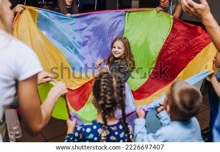 Little girl of preschool age, child dancing, spinning indoors in a competition with a long multi-colored cloth animator in honor of the birthday. Royalty-Free Stock Photo #2226697407