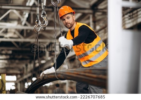 Man working at steel factory by th crane lifting steel