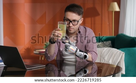 Young man with bionic arm sit down and put medicine in glass of water at home. Guy with robotic hand prosthesis dissolve pin in glass of water.