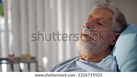 Close up portrait of senior man with nasal breathing tube lying in hospital bed. Ill aged male patient with oxygen cannula breathing heavily having respiratory disease Royalty-Free Stock Photo #2226719503
