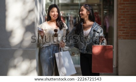 Image of two happy girlfriends walking on the city street with shopping bags. 