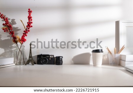 Creative working desk with camera, picture frame, books and paper cup of coffee.