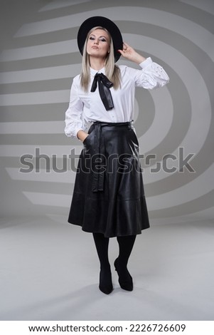 Business woman in black skirt and white shirt, full length studio portrait on gray background