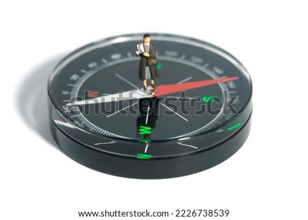 Miniature people toy figure photography. A woman holding photo frame standing above compass, searching missing person, isolated on white background. Image photo