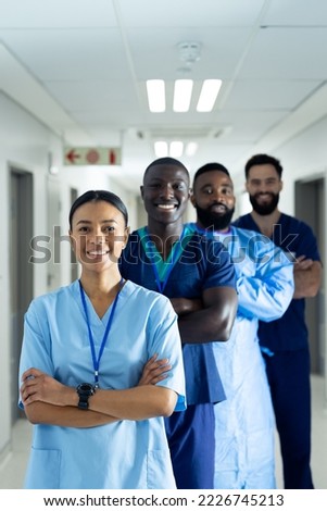 Vertical portrait of diverse group of smiling healthcare workers in line in corridor, copy space. Hospital, medical and healthcare services.
